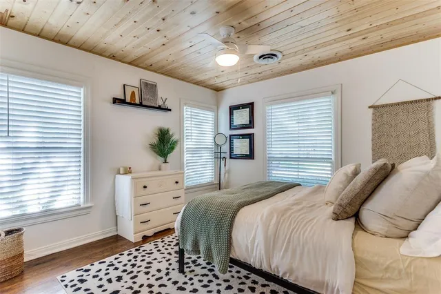 a bedroom with a bed a dresser and next to a window