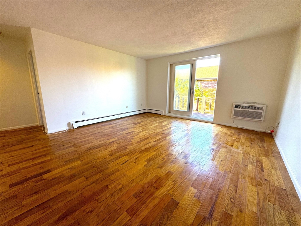 44 Westgate Road, Unit 5 Boston, MA 02467 - Photo 3 of 15 a view of an empty room with wooden floor and a window