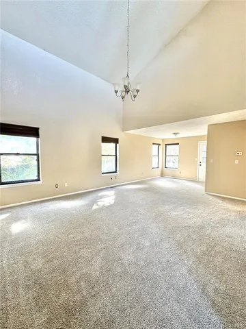 an empty room with windows and chandelier fan