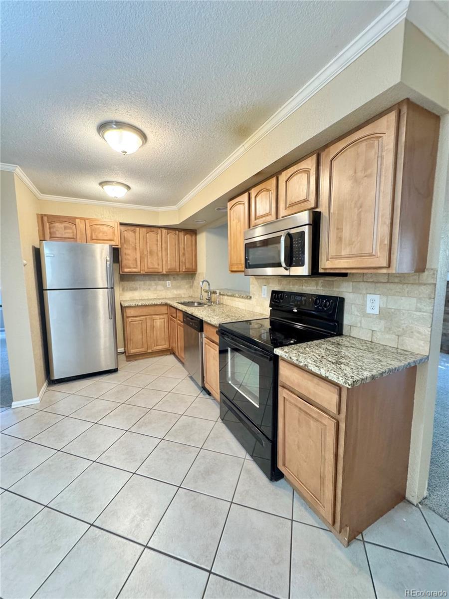 17938 East Amherst Avenue Aurora, CO 80013 - Photo 7 of 16 a kitchen with stainless steel appliances granite countertop a stove and a refrigerator