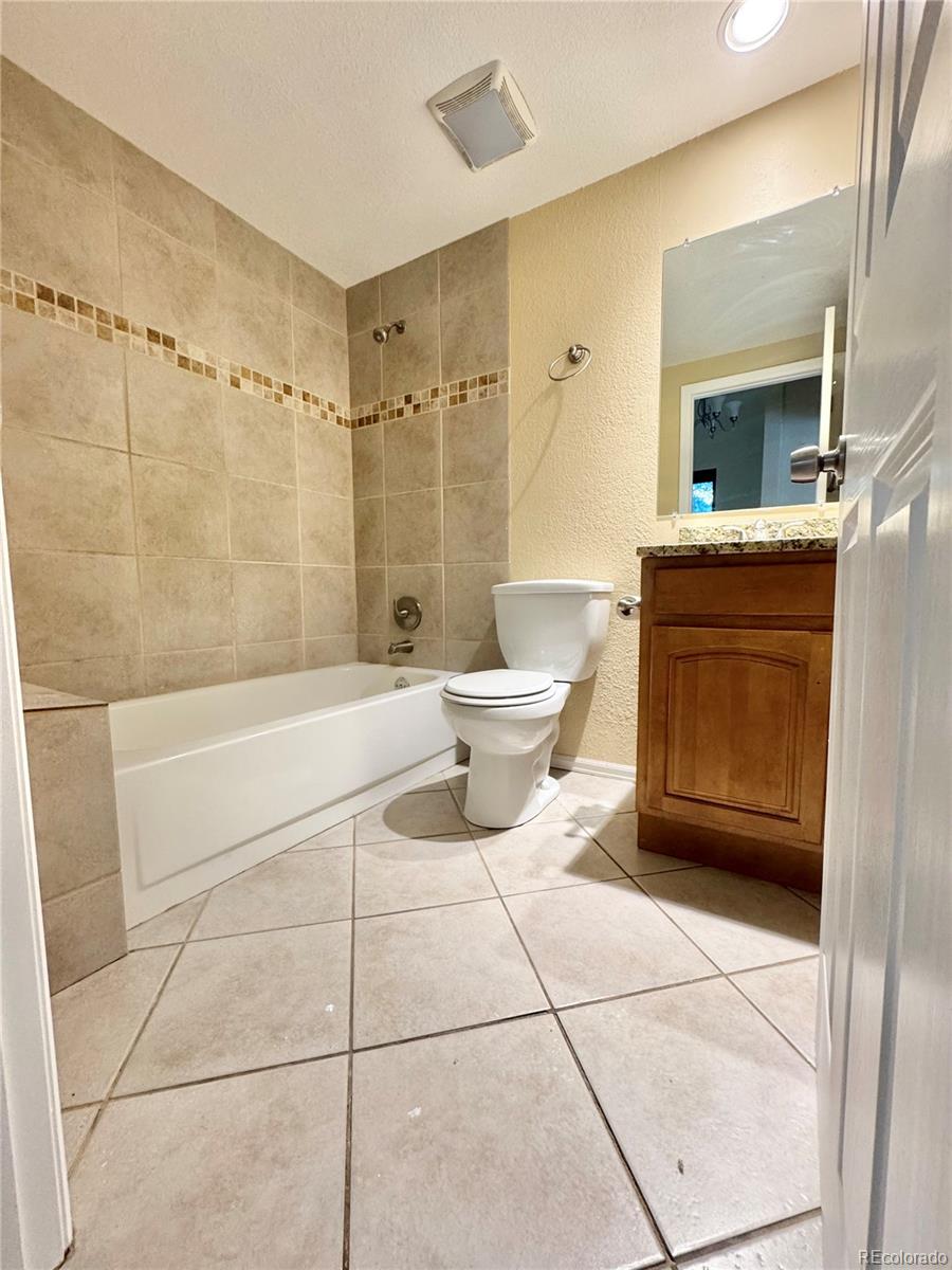 17938 East Amherst Avenue Aurora, CO 80013 - Photo 8 of 16 a bathroom with a toilet a sink a mirror and bathtub