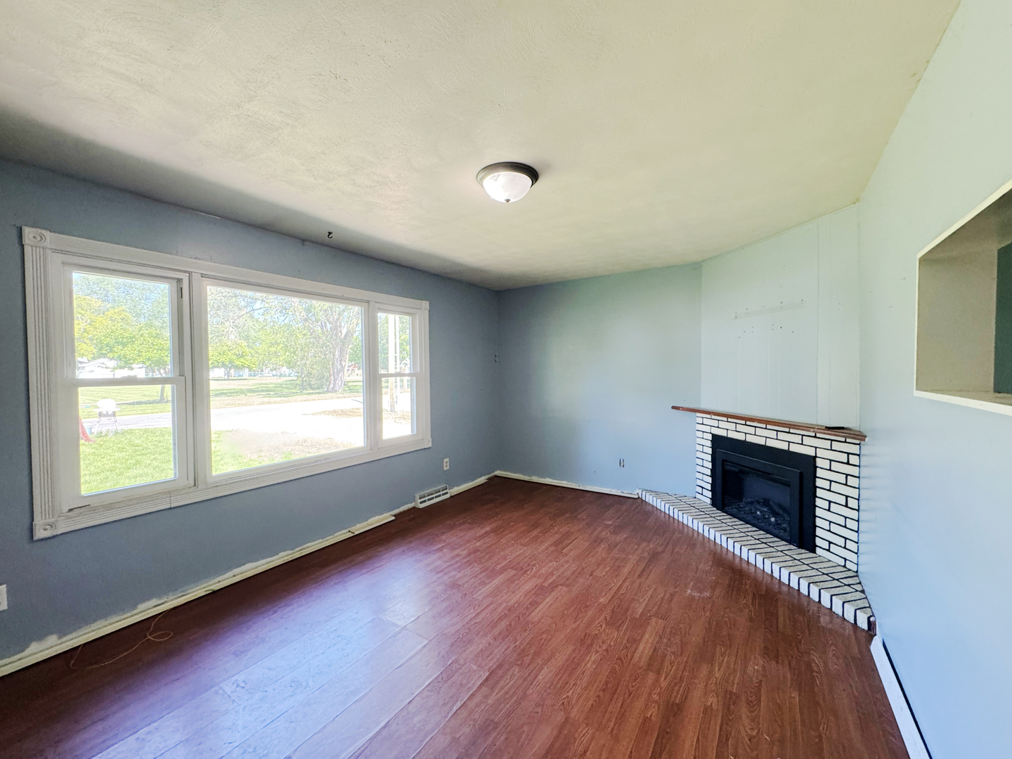 310 North 3rd Avenue Chenoa, IL 61726 - Photo 7 of 23 an empty room with wooden floor fireplace and windows