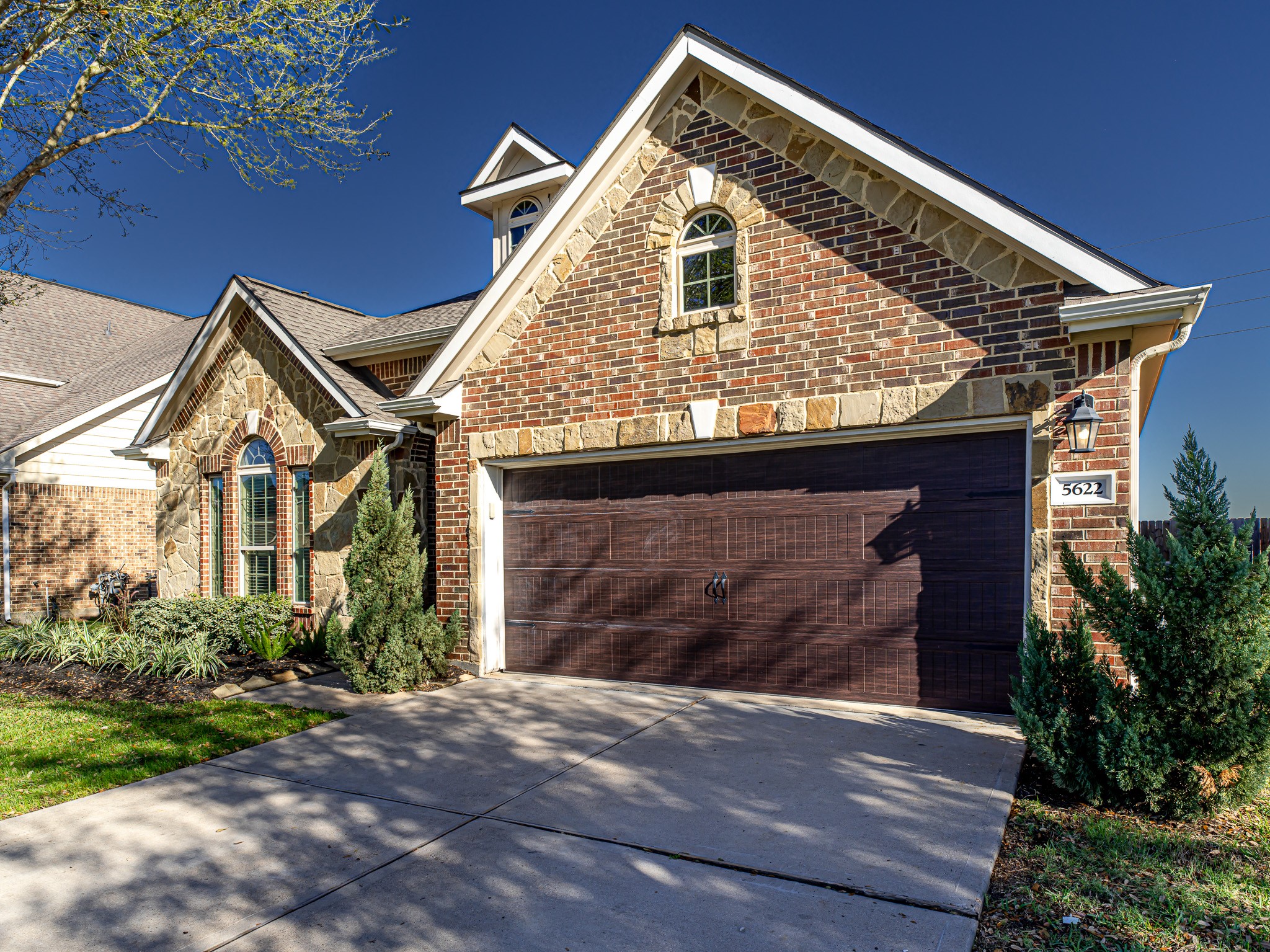 5622 Maxon Court Rosenberg, TX 77471 - Photo 2 of 23 Admire the rich texture of the stone and brick, perfectly complemented by a beautiful garage door and arched window above.