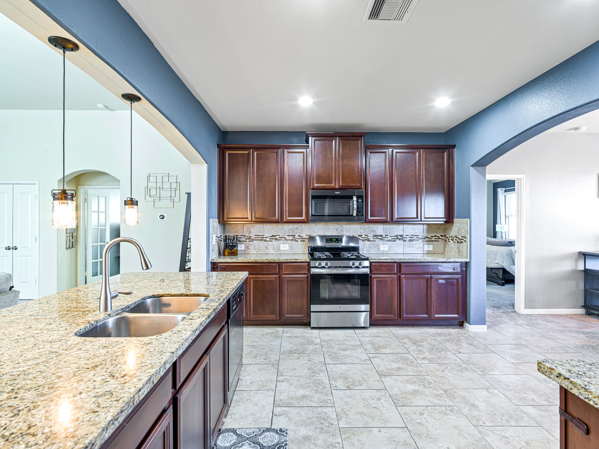 5622 Maxon Court Rosenberg, TX 77471 - Photo 9 of 23 Your expansive kitchen has it all! Featuring recessed lighting, rich cabinetry and premium granite countertops. The sleek gas range and designer backsplash with quartz accents perfectly compliment the massive island, complete with pendant lighting and an undermount sink.