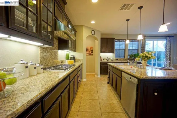 a kitchen with kitchen island granite countertop a sink counter top space and stainless steel appliances