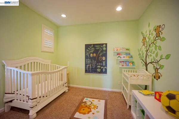a view of a bedroom with wooden floor & wall paintings