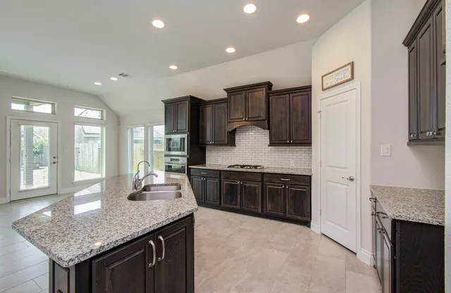 a large kitchen with granite countertop a sink and stove