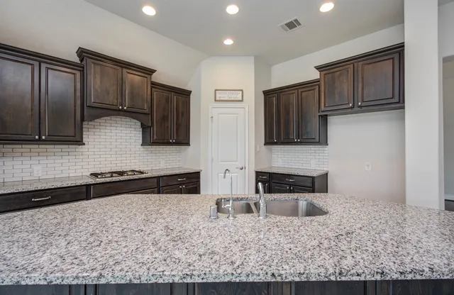 a kitchen with stainless steel appliances granite countertop a stove a sink and a microwave