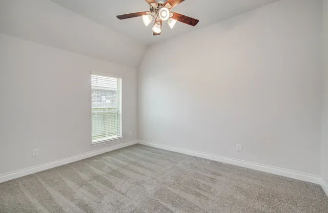 an empty room with windows and chandelier fan