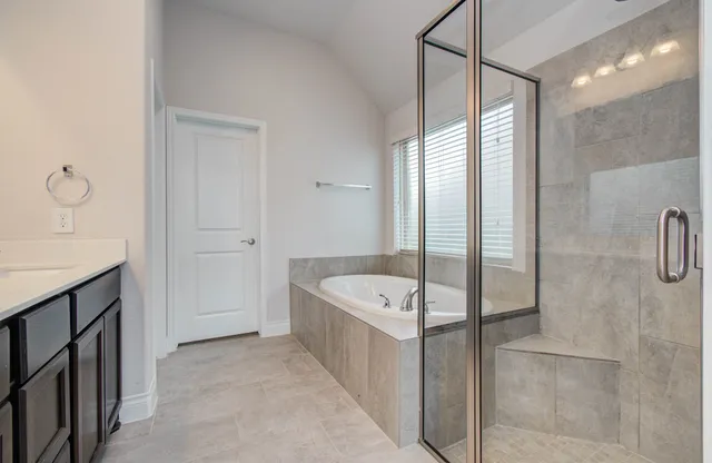 a spacious bathroom with a tub sink shower and mirror