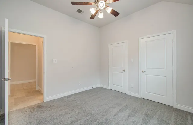 a view of an empty room and chandelier fan