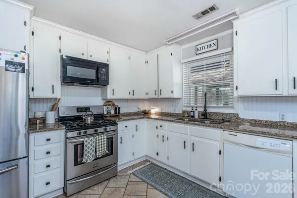 a kitchen with granite countertop white cabinets sink and stainless steel appliances