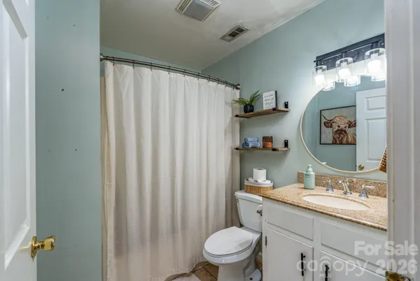 a bathroom with a granite countertop sink toilet and a mirror