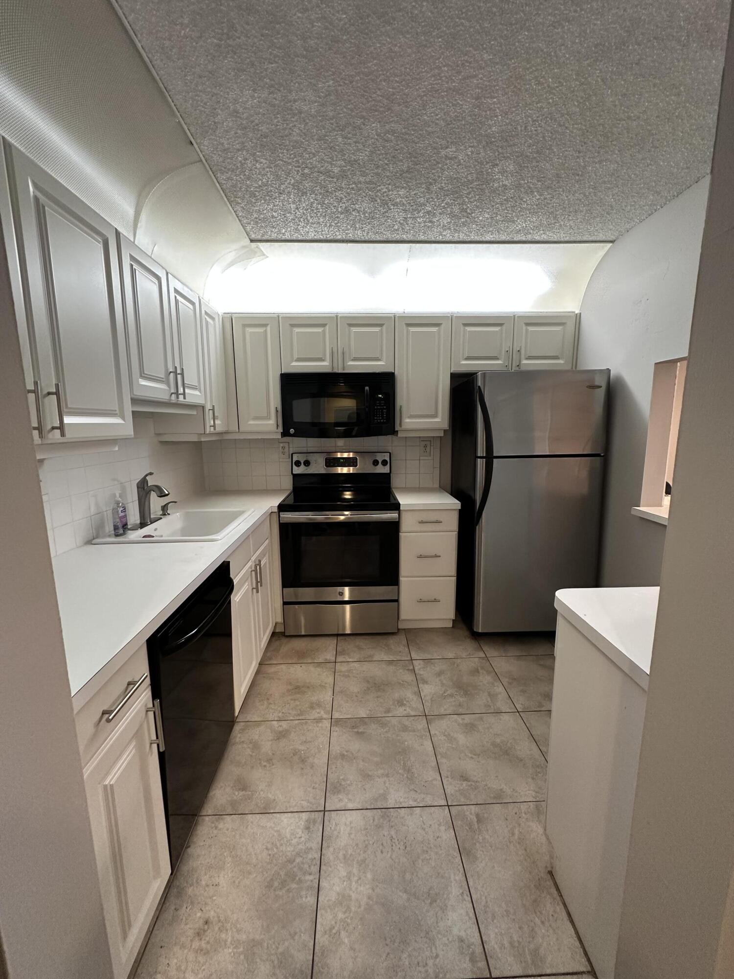 a kitchen with a sink a microwave a refrigerator and cabinets