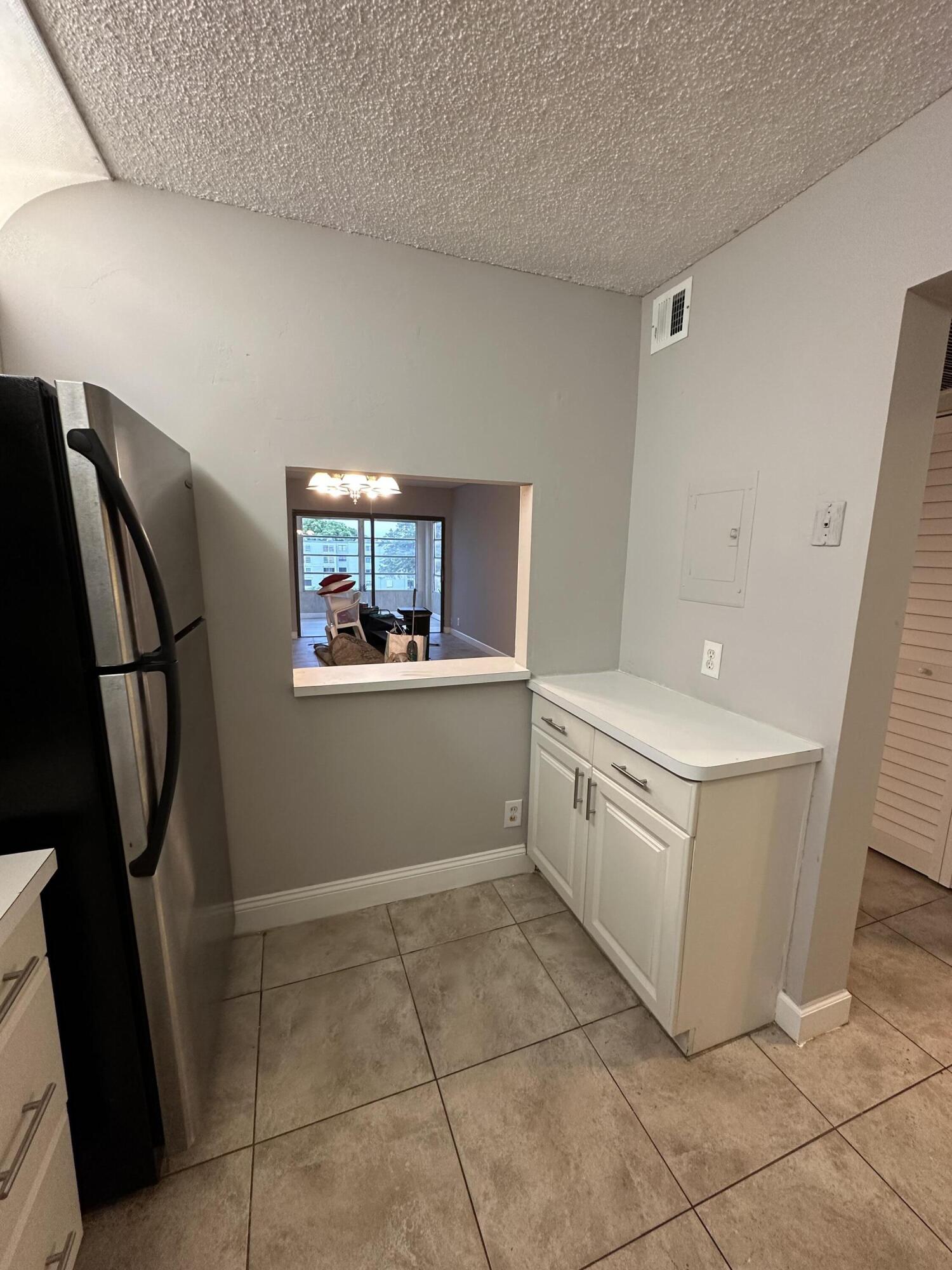 9370 Southwest 8th Street, Unit 419 Boca Raton, FL 33428 - Photo 5 of 18 a kitchen with white cabinets and white appliances