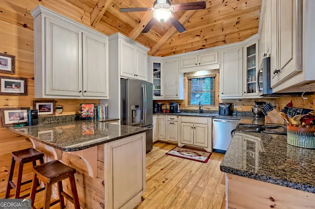 a kitchen with stainless steel appliances granite countertop a refrigerator a stove and white cabinets with wooden floors