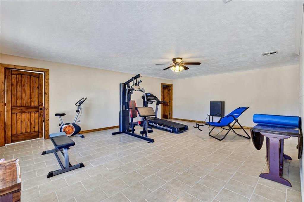 11591 Farm To Market 59 Athens, TX 75751 - Photo 24 of 40 Basement room featuring neutral-toned walls, tile flooring, and rustic wood-paneled doors. Right now this multi purpose space is the exercise room - BUT what would you do with this dream space?