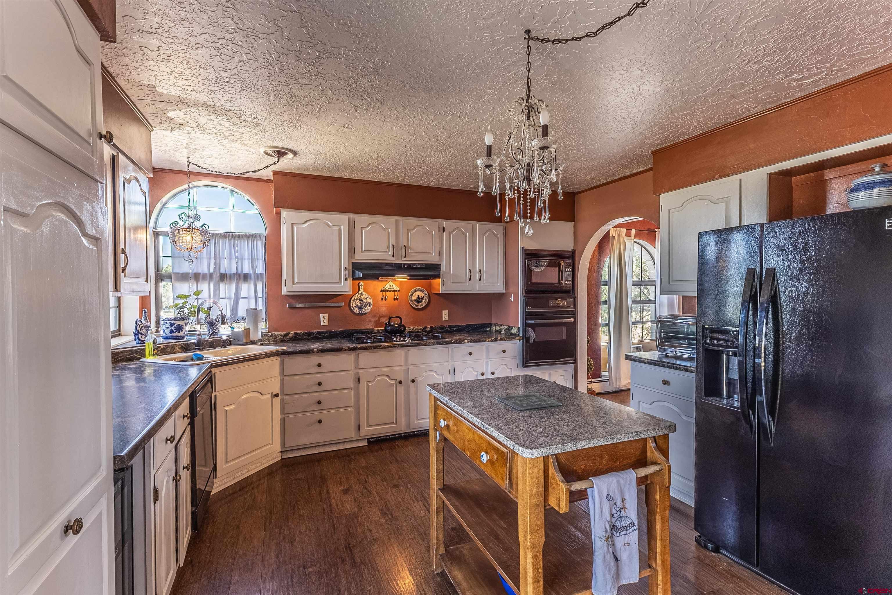 5510 Rinconada Street Farmington, NM 87402 - Photo 19 of 45 a kitchen with stainless steel appliances granite countertop a refrigerator a stove a sink dishwasher a dining table and chairs with wooden floor