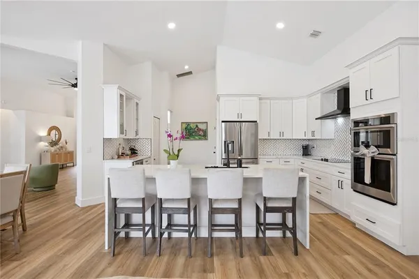 a kitchen with stainless steel appliances a dining table chairs microwave and stove top oven