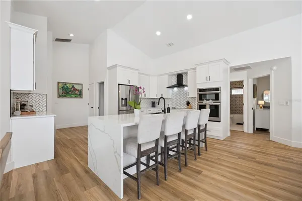 a kitchen with stainless steel appliances a dining table chairs and wooden floor