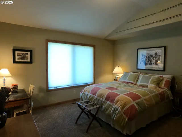 a bedroom with a bed and a lamp on dresser