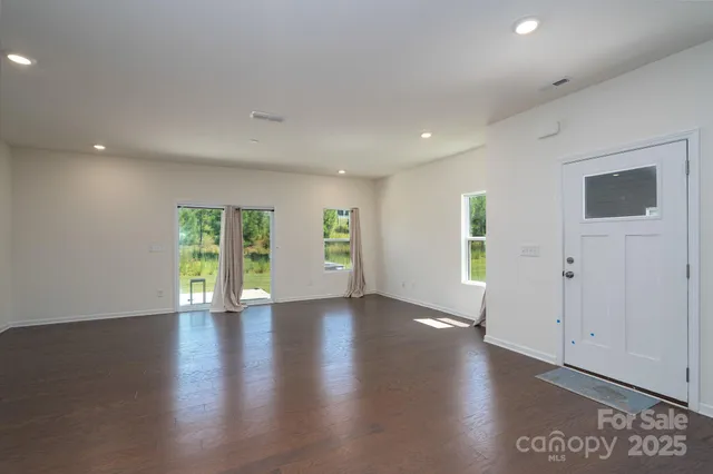 a view of an empty room with wooden floor and windows