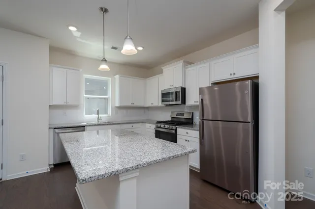 a kitchen with stainless steel appliances granite countertop a refrigerator a sink a stove a microwave and island