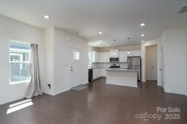 a view of kitchen with kitchen island stainless steel appliances refrigerator stove microwave and cabinets