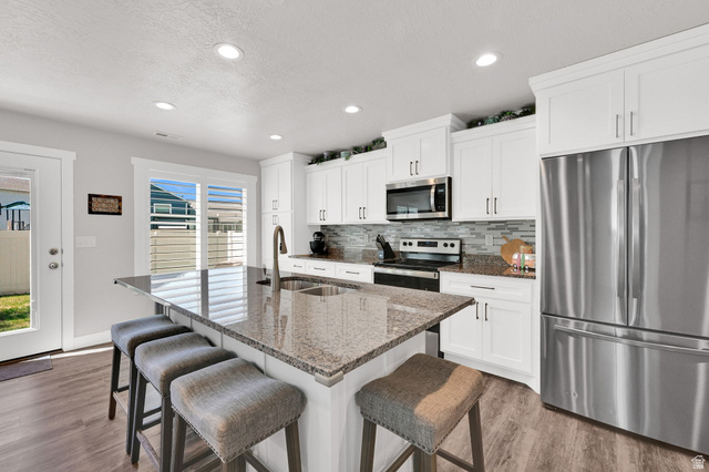 2777 West 4175th Street South, Unit 232 Roy, UT 84067 - Photo 6 of 27 Modern kitchen featuring white shaker cabinetry, granite countertops, stainless steel appliances, a tile backsplash, and LVP flooring