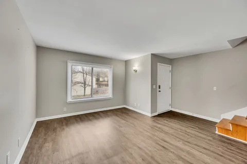 an empty room with wooden floor and window