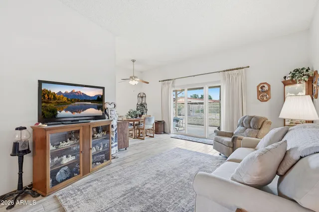 a living room with furniture a flat screen tv and a floor to ceiling window