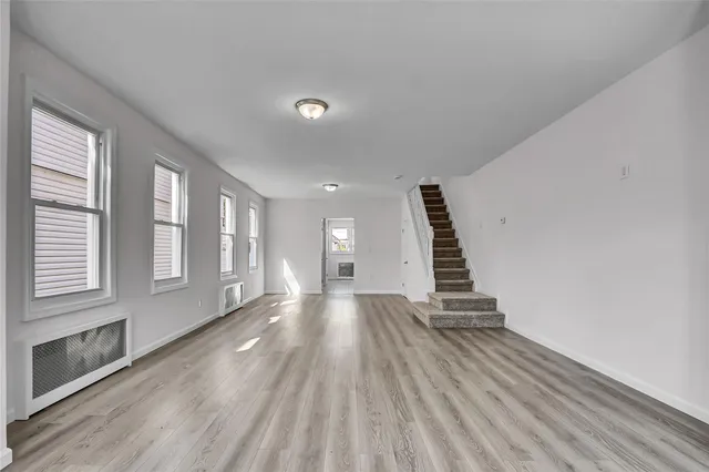 a view of an empty room with wooden floor and windows
