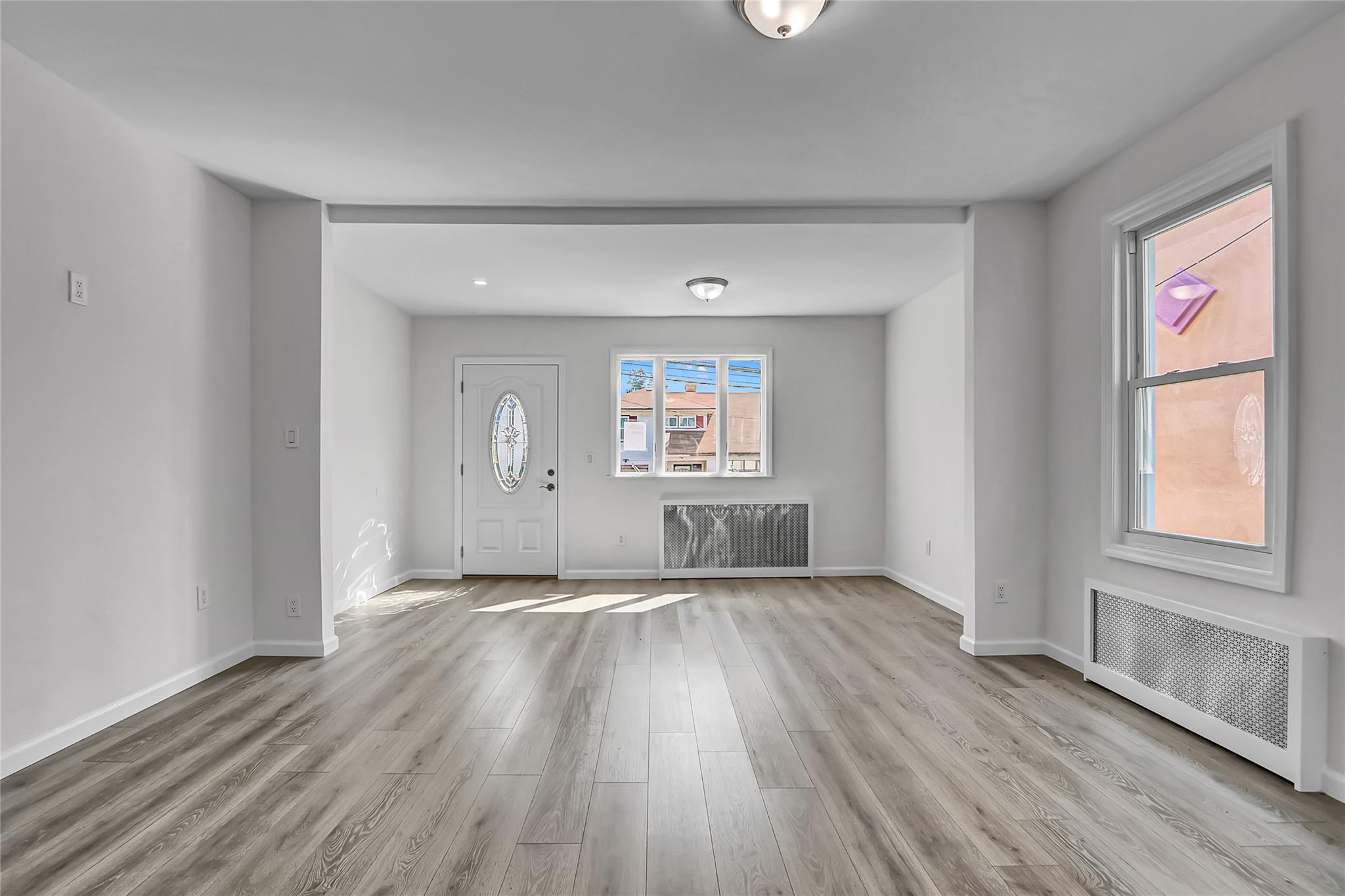 111-32 116th Street Queens, NY 11420 - Photo 5 of 18 an empty room with wooden floor and windows