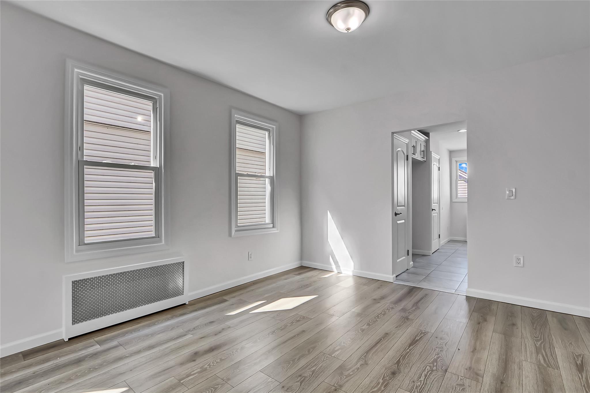 111-32 116th Street Queens, NY 11420 - Photo 6 of 18 an empty room with wooden floor and windows