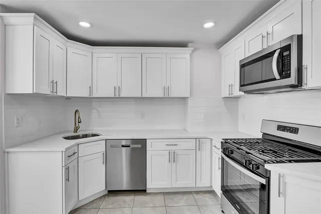 a kitchen with white cabinets stainless steel appliances and sink