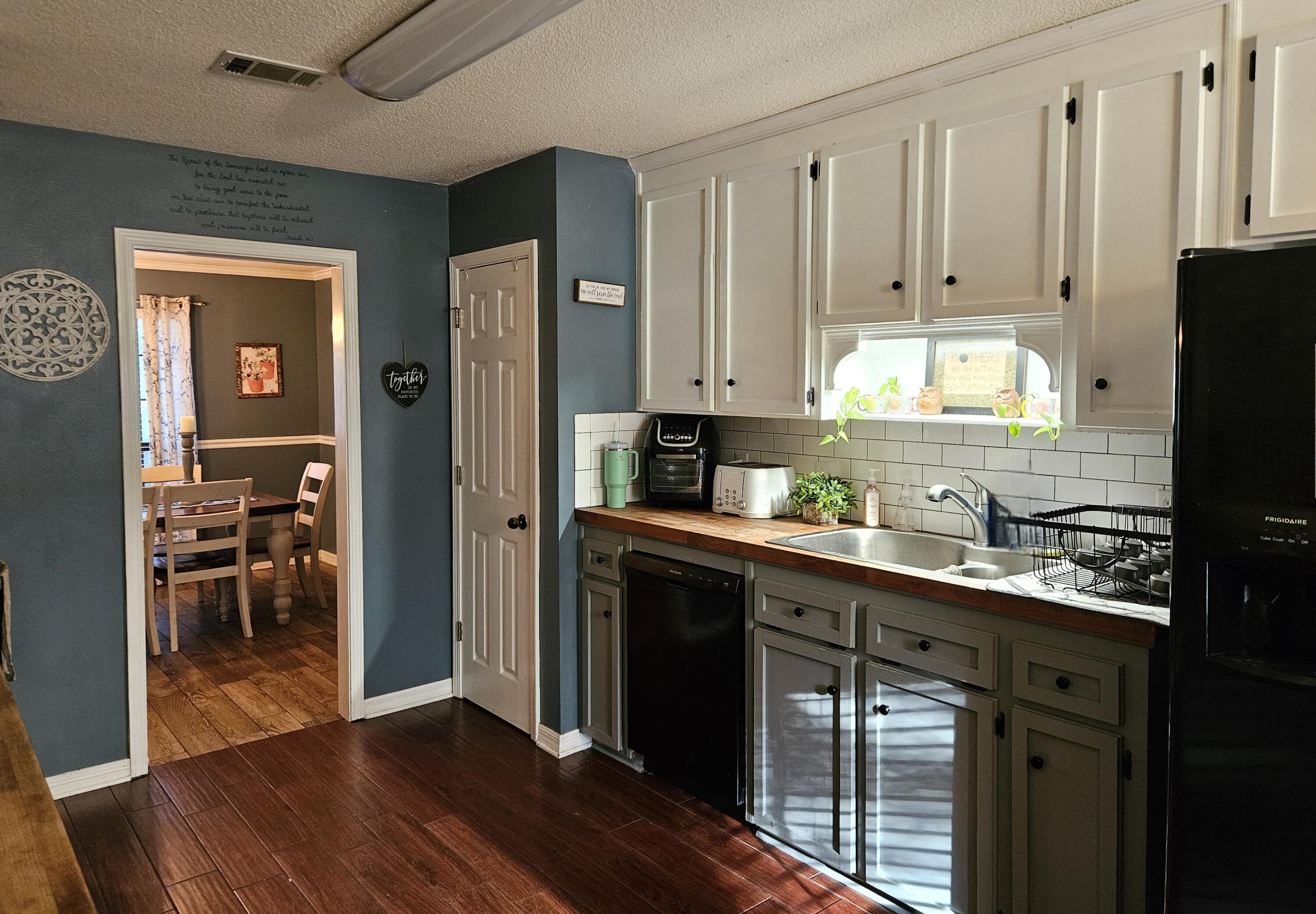 108 Mohawk Trail Crestview, FL 32536 - Photo 14 of 39 a kitchen with stainless steel appliances granite countertop a refrigerator a sink dishwasher and white cabinets with wooden floor