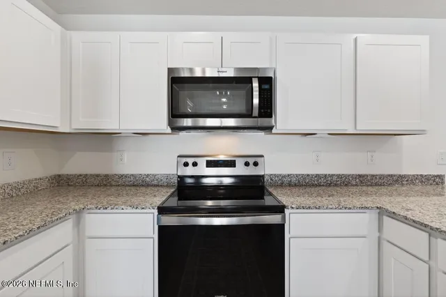 a kitchen with stainless steel appliances granite countertop white cabinets and a stove top oven
