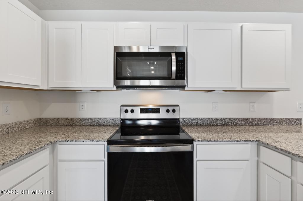 45124 Red Brick Drive Callahan, FL 32011 - Photo 13 of 54 a kitchen with stainless steel appliances granite countertop white cabinets and a stove top oven
