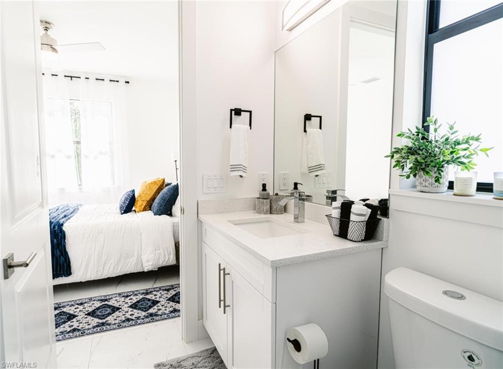 907 Homestead Road South Lehigh Acres, FL 33974 - Photo 23 of 43 Contemporary bathroom featuring a single vanity with quartz countertop, white cabinetry with silver-tone hardware, and an undermount sink with a chrome faucet