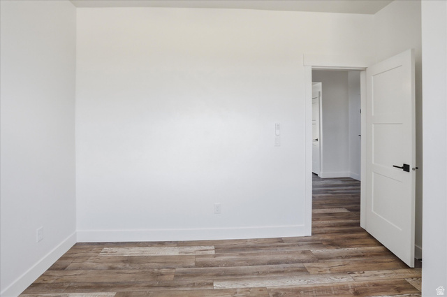 1315 West 3200 South, Unit 17 Perry, UT 84302 - Photo 22 of 58 Room with wood-finish flooring, white walls, white baseboards, and a white interior door with black hardware