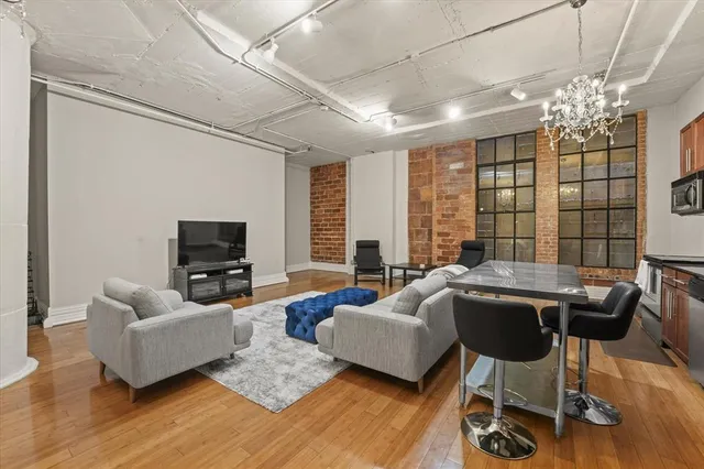 a living room with furniture a chandelier a large window and wooden floor