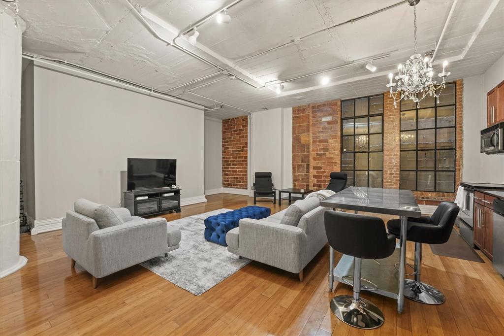 a living room with furniture a chandelier a large window and wooden floor