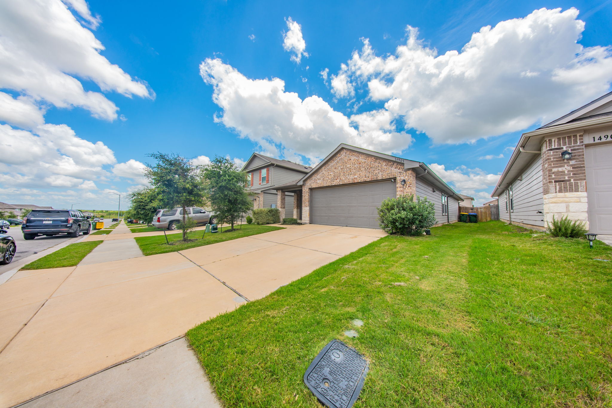 14903 Tuff Road Manor, TX 78653 - Photo 20 of 25 A classic brick and siding residence with a two-car garage and manicured lawn.