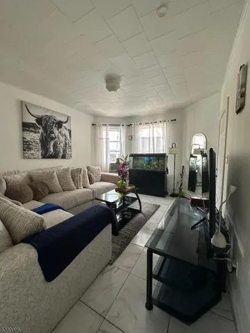 a living room with furniture a flat screen tv and a refrigerator