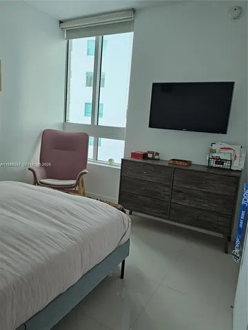 a bedroom with a bed television and a window