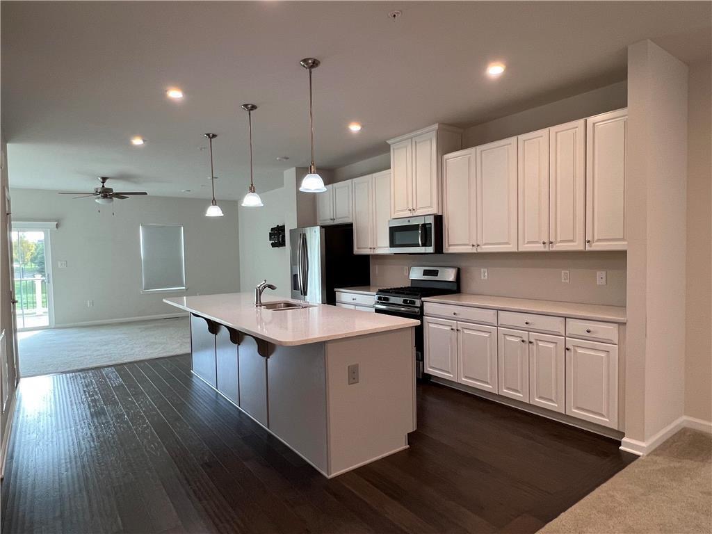 Rich dark wood flooring anchors this light-filled culinary space equipped with a central prep island.