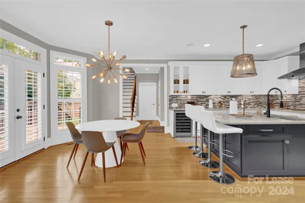 a kitchen with stainless steel appliances kitchen island granite countertop a table chairs sink and wooden floor