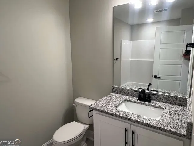 a bathroom with a granite countertop sink toilet and a mirror