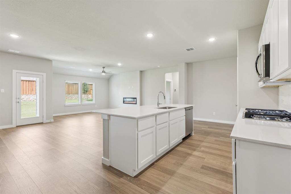 1468 Companero Street Haslet, TX 76052 - Photo 27 of 29 a large white kitchen with wooden floor and a sink