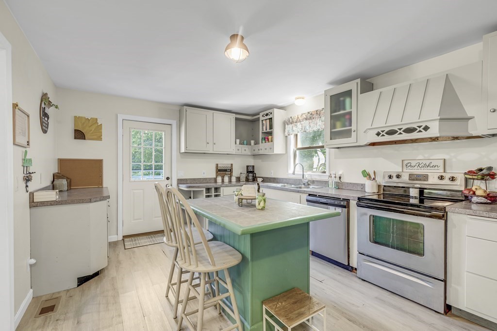 24 Sand Hill Road Salisbury, MA 01952 - Photo 8 of 28 a kitchen with stainless steel appliances granite countertop a stove a sink dishwasher a microwave oven and a dining table with wooden cabinet